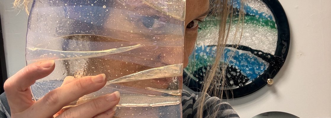 the artist stevie davies, hold up a piece of fused glass